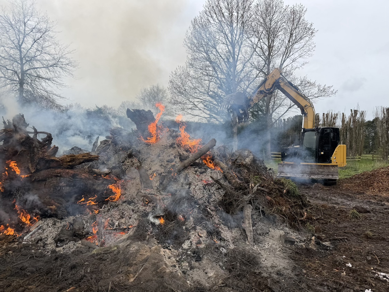 Excavator beside a vegetation burn during a shelterbelt clean-up